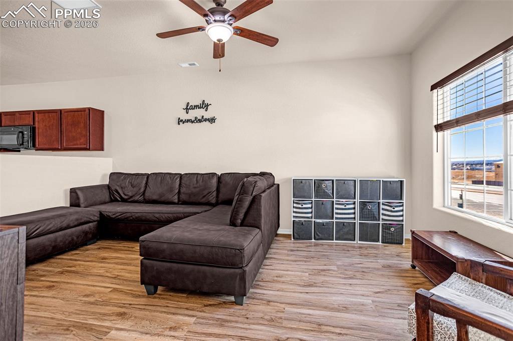 Living area with light wood finished floors and ceiling fan