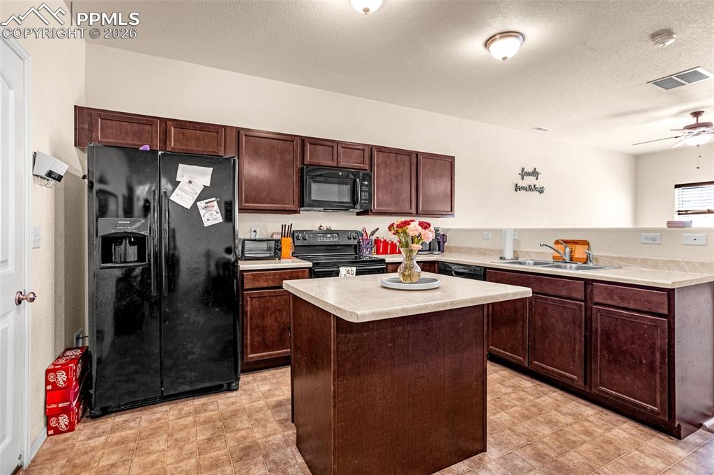 Kitchen with black appliances, light countertops, ceiling fan, a textured ceiling, and dark wood finish cabinets