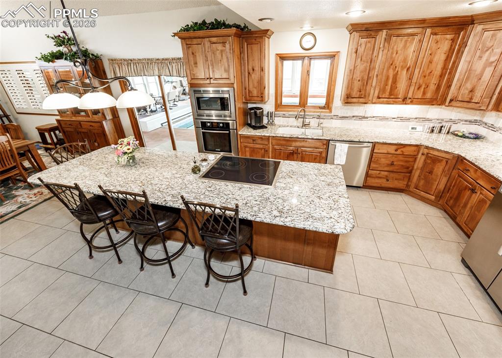 This kitchen features durable granite countertops, the convenience of two ovens, and a smooth electric oven top. It's equipped with high-quality Bosch appliances, incorporating the thoughtful design of slow-close drawers, enhanced by the warm ambiance of canned lighting, and finished with custom hardwood cabinetry.