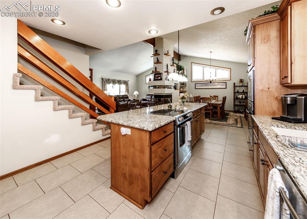 This kitchen features durable granite countertops, the convenience of two ovens, and a smooth electric oven top. It's equipped with high-quality Bosch appliances, incorporating the thoughtful design of slow-close drawers, enhanced by the warm ambiance of canned lighting, and finished with custom handwood cabinetry.