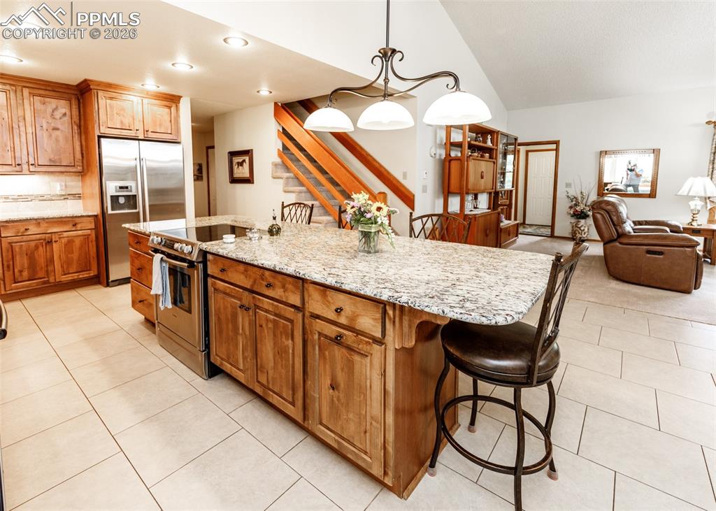 This kitchen features durable granite countertops, the convenience of two ovens, and a smooth electric oven top. It's equipped with high-quality Bosch appliances, incorporating the thoughtful design of slow-close drawers, enhanced by the warm ambiance of canned lighting, and finished with custom hardwood cabinetry.