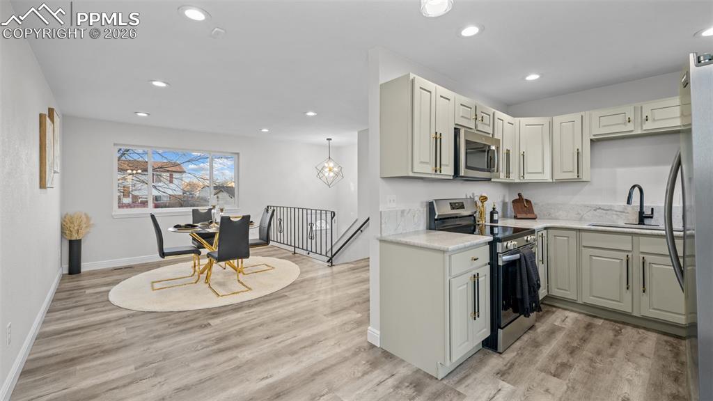 Kitchen with stainless steel appliances, light wood-style flooring, recessed lighting, and light stone countertops