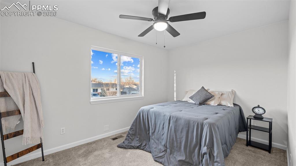 Bedroom with light colored carpet and a ceiling fan