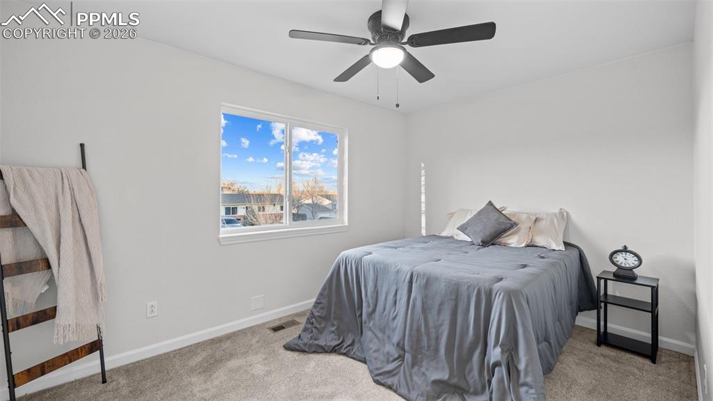 Bedroom with light colored carpet and a ceiling fan