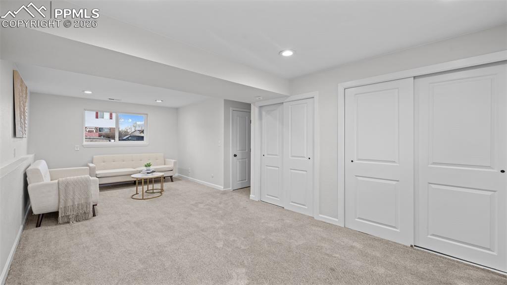 Living area with light colored carpet and recessed lighting