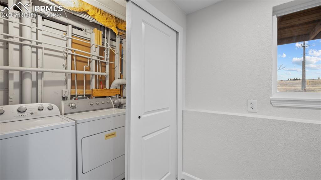 Laundry area featuring a textured wall and washing machine and clothes dryer