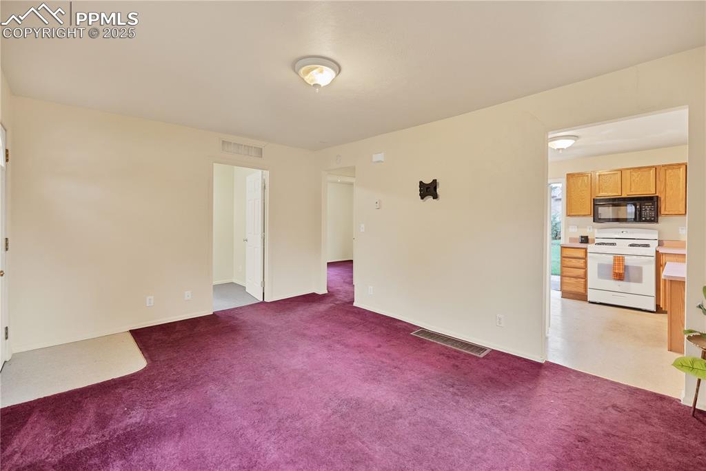 Empty room featuring light colored carpet and baseboards