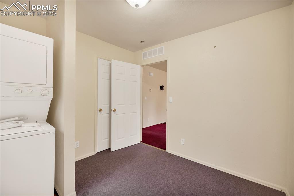 Laundry area with carpet and stacked washer and clothes dryer