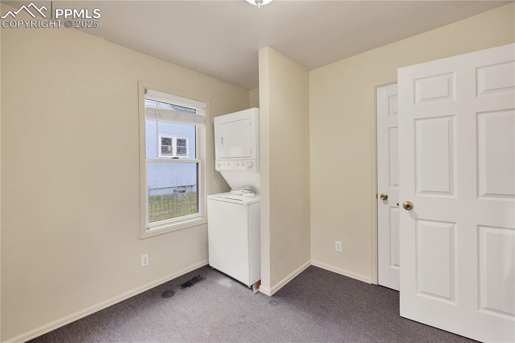 Washroom featuring carpet and stacked washer / drying machine