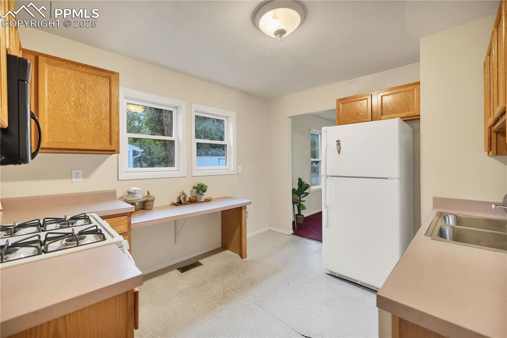 Kitchen with white appliances, light countertops, and brown cabinetry