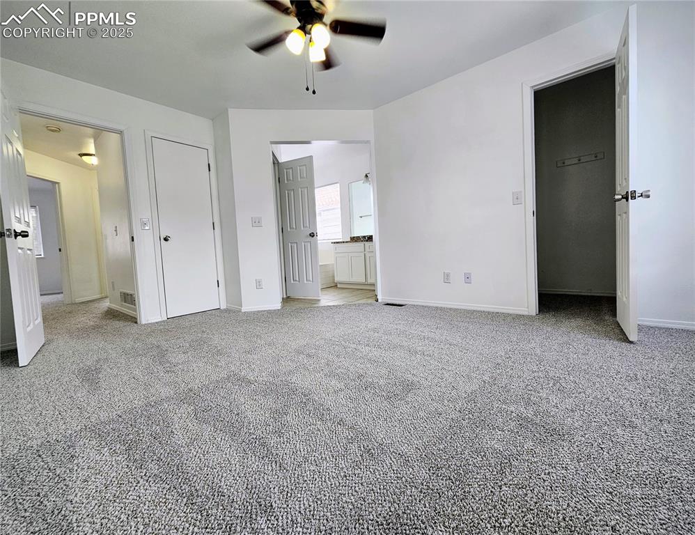 Unfurnished bedroom featuring light carpet, connected bathroom, and ceiling fan