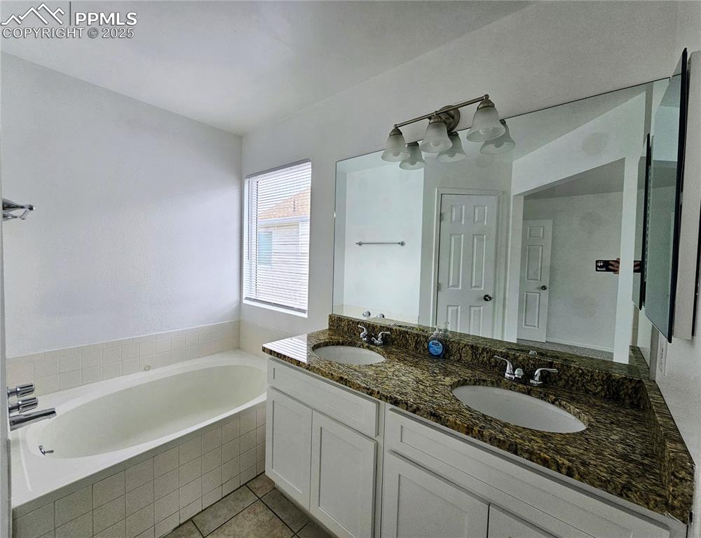 Full bath featuring a bath, double vanity, and light tile patterned flooring