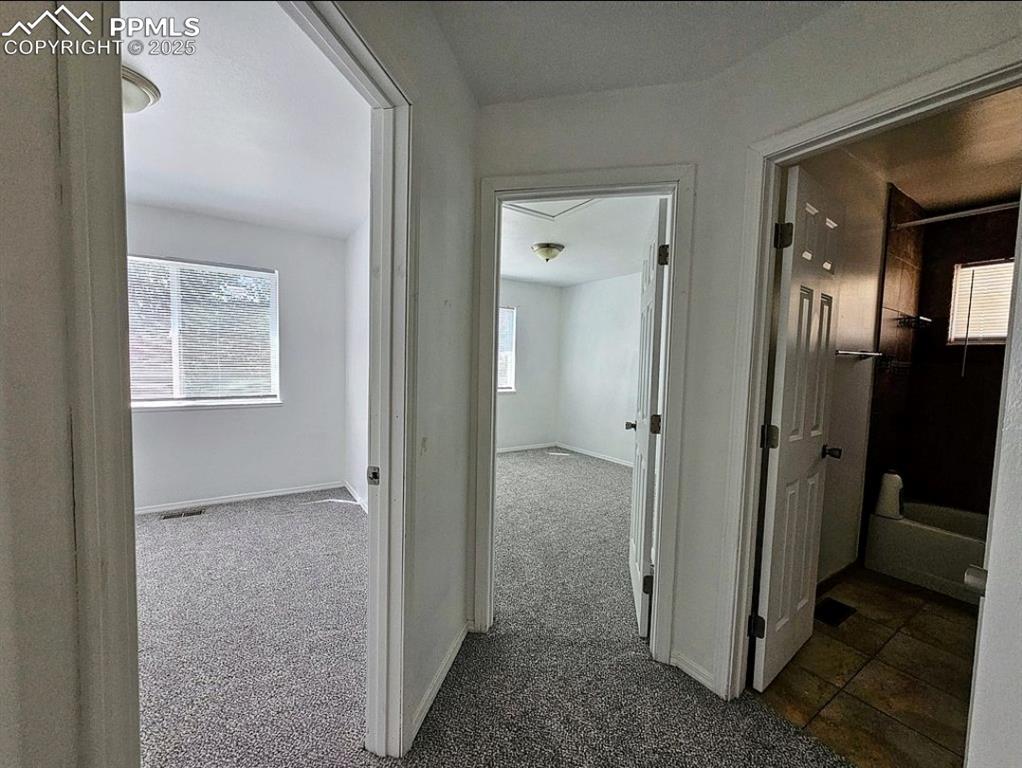 Hallway with dark carpet and baseboards