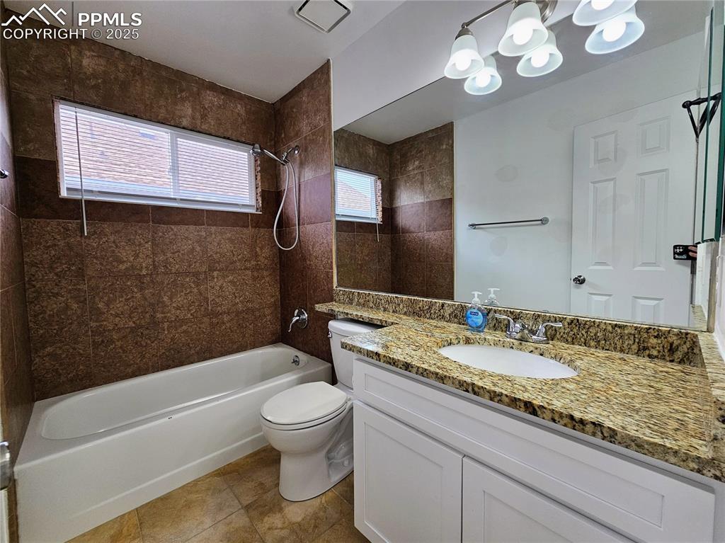 Bathroom with bathing tub / shower combination, vanity, and light tile patterned floors
