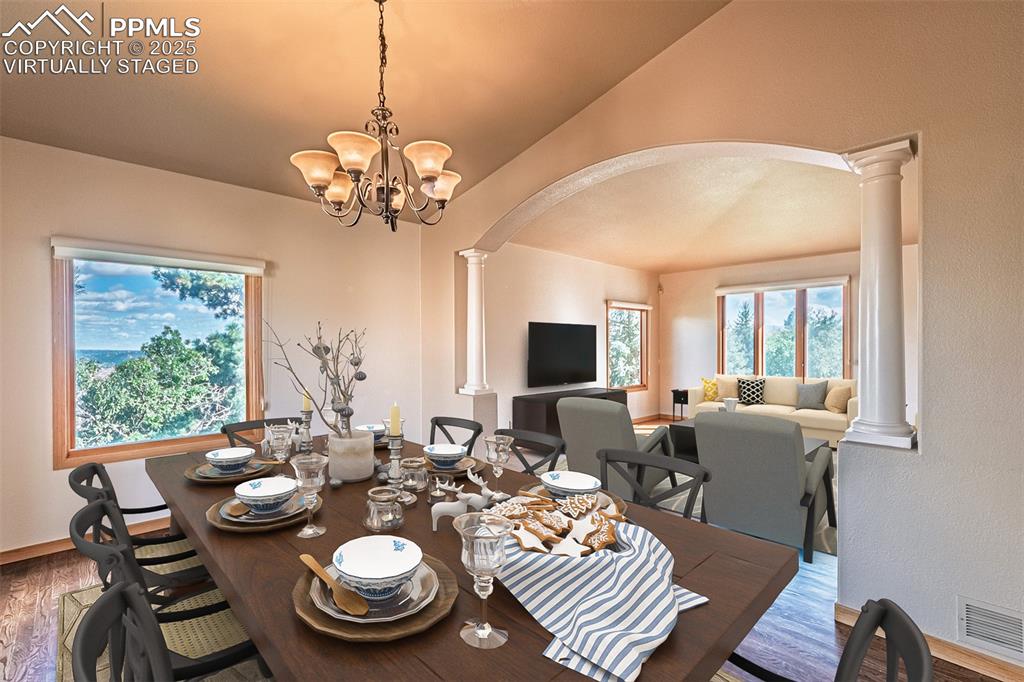 Virtually Staged
Dining space featuring arched walkways, decorative columns, wood finished floors, a chandelier, and a textured wall