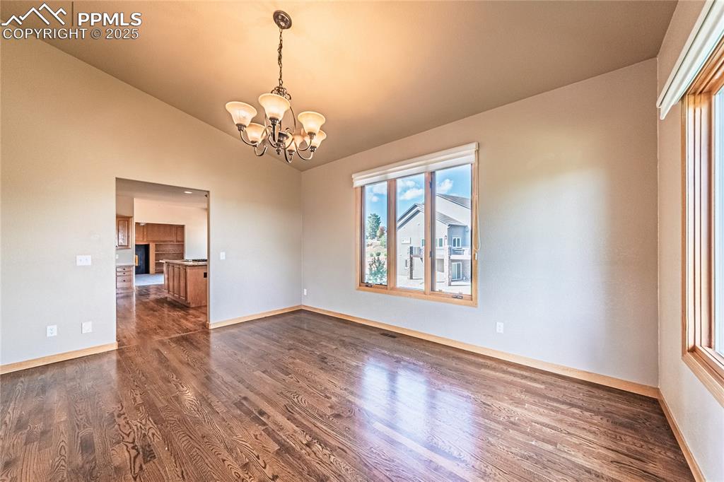 Dining area with dark wood-style flooring, a chandelier, and lofted ceiling
