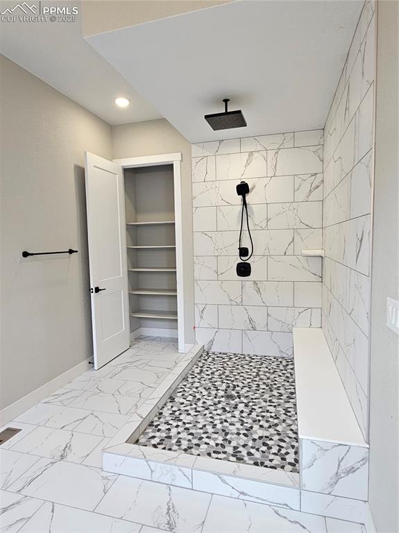 Full bathroom featuring tiled shower, light marble finish floors, recessed lighting, and built in shelves