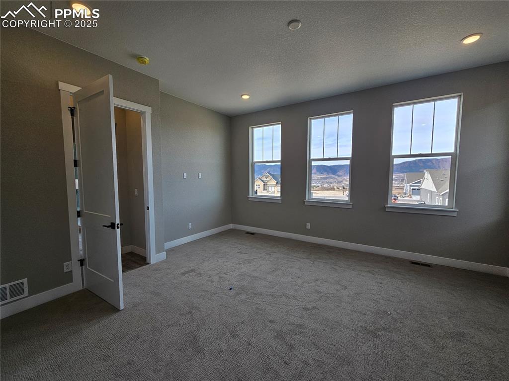 Carpeted empty room featuring a textured ceiling and recessed lighting