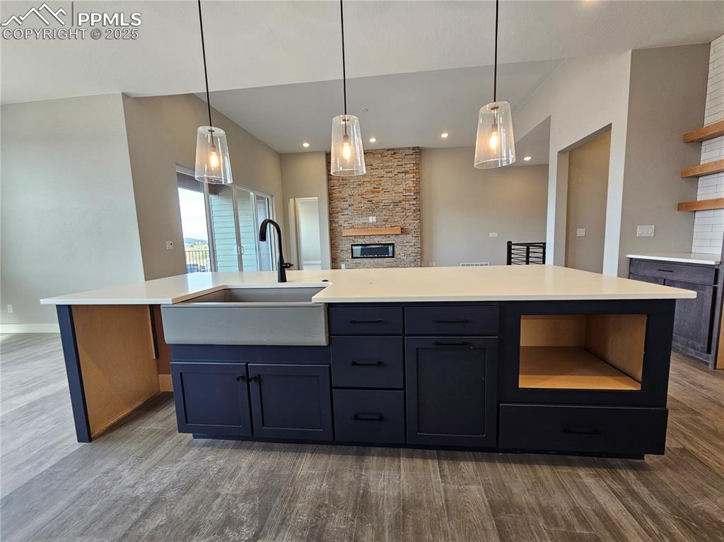 Kitchen featuring open shelves, hanging light fixtures, dark wood finished floors, light stone counters, and recessed lighting