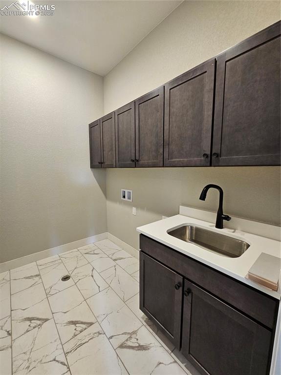 Laundry room with light marble finish floors, washer hookup, and cabinet space