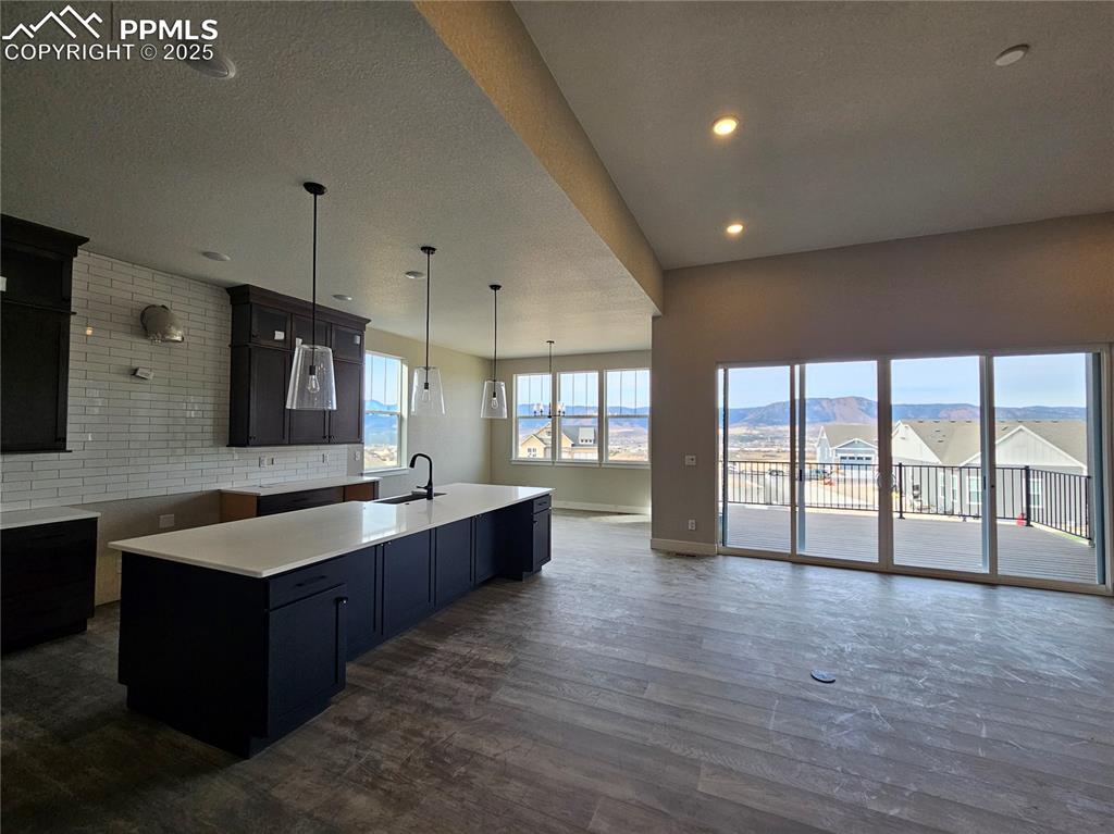 Kitchen with decorative light fixtures, open floor plan, a textured ceiling, tasteful backsplash, and dark wood finished floors