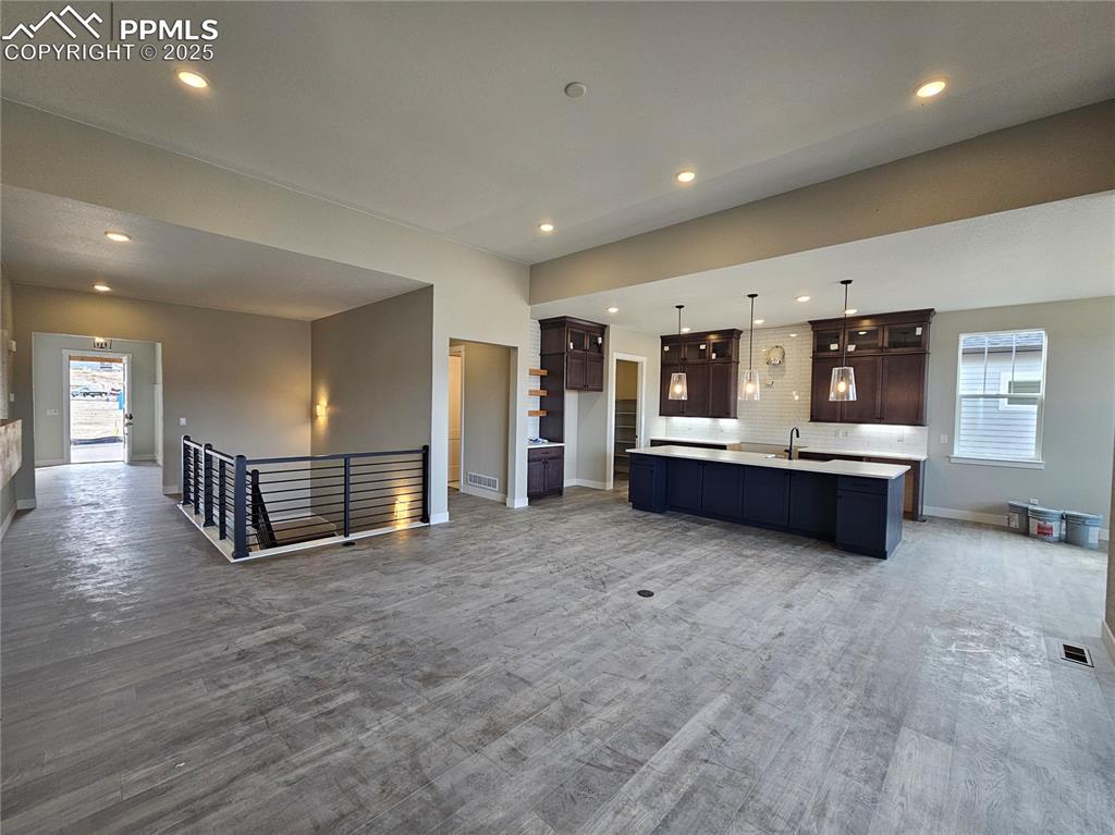 Kitchen with healthy amount of natural light, open floor plan, tasteful backsplash, an island with sink, and recessed lighting