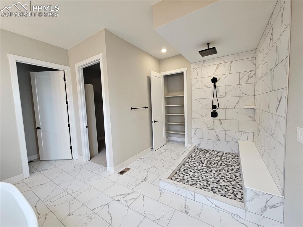 Bathroom with a walk in closet, light marble finish floors, tiled shower, recessed lighting, and a bathtub