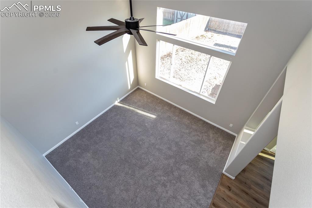 The stairs overlook the 2 story living room with lovely ceiling fan.