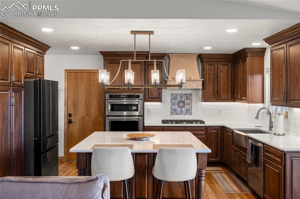Kitchen with gas range, large island, quartz countertops and tons of cabinetry. 