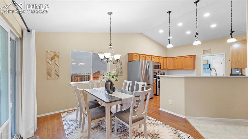 Dining space with vaulted ceiling, light wood-style flooring, a chandelier, and recessed lighting