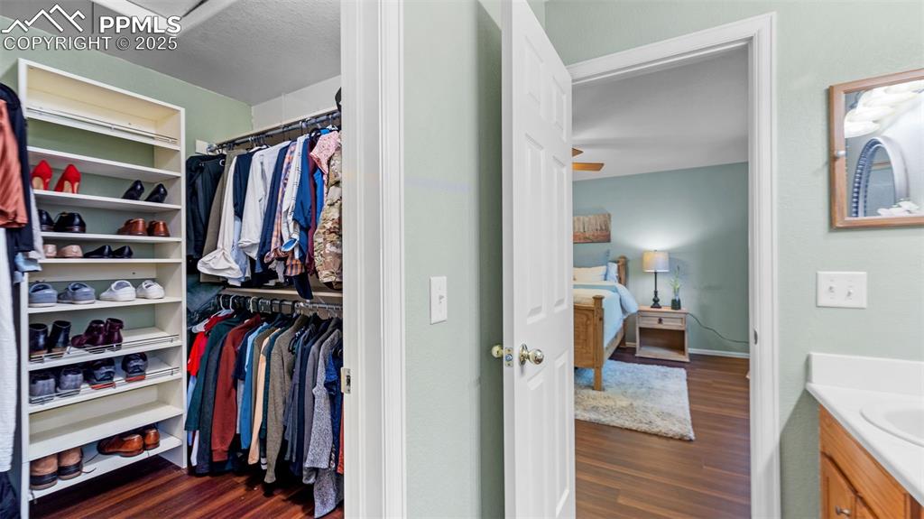Walk in closet with dark wood-type flooring