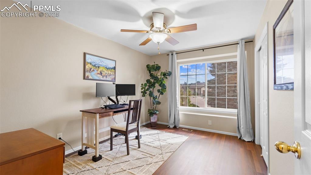 Office area with light wood finished floors and a ceiling fan
