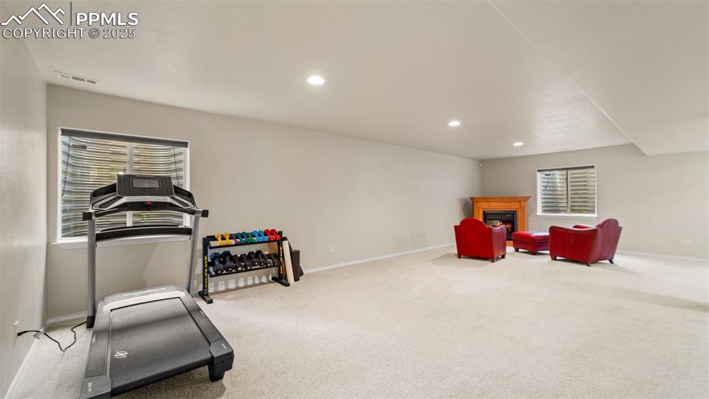 Living area with a fireplace, light colored carpet, recessed lighting, and healthy amount of natural light