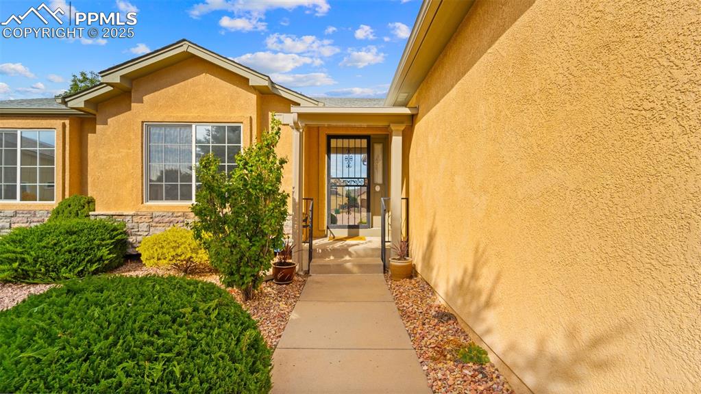 Doorway to property featuring stucco siding and stone siding