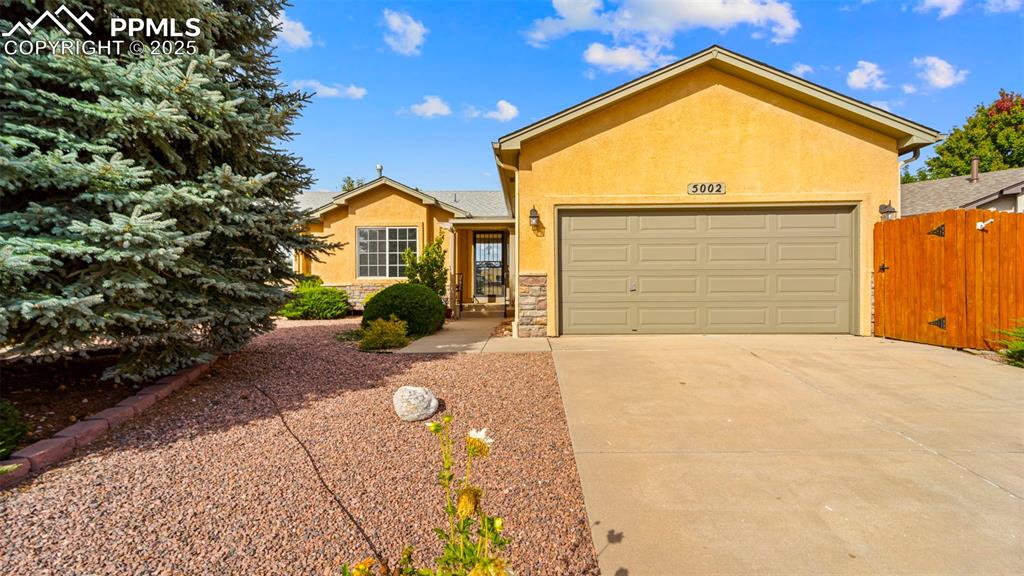 Ranch-style home featuring stucco siding, driveway, an attached garage, and stone siding