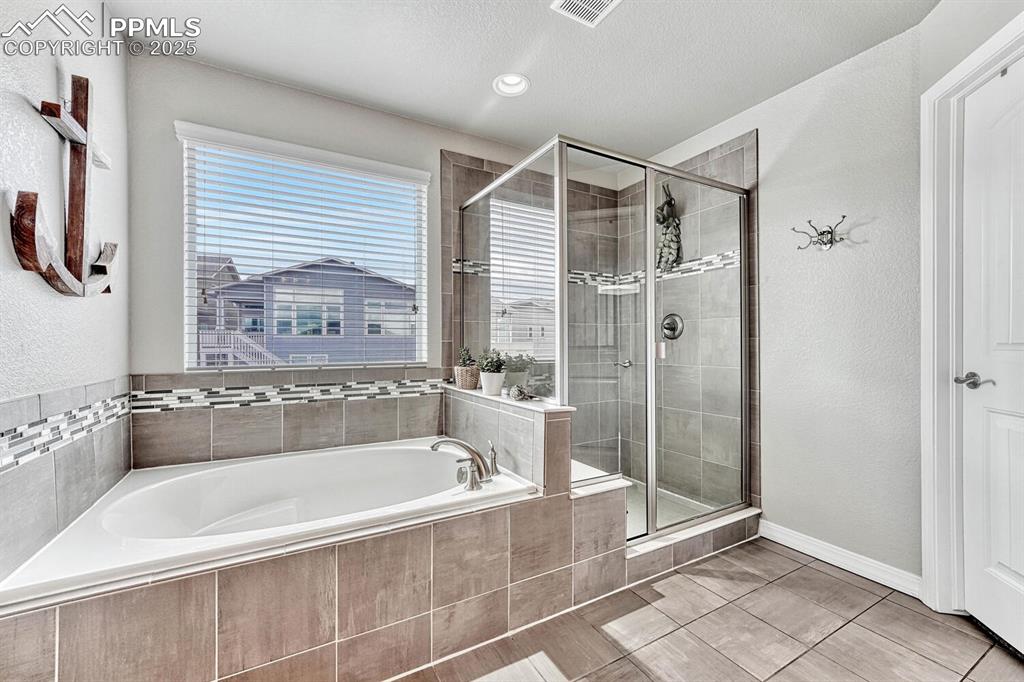 Full bath with a shower stall, a bath, baseboards, and visible vents