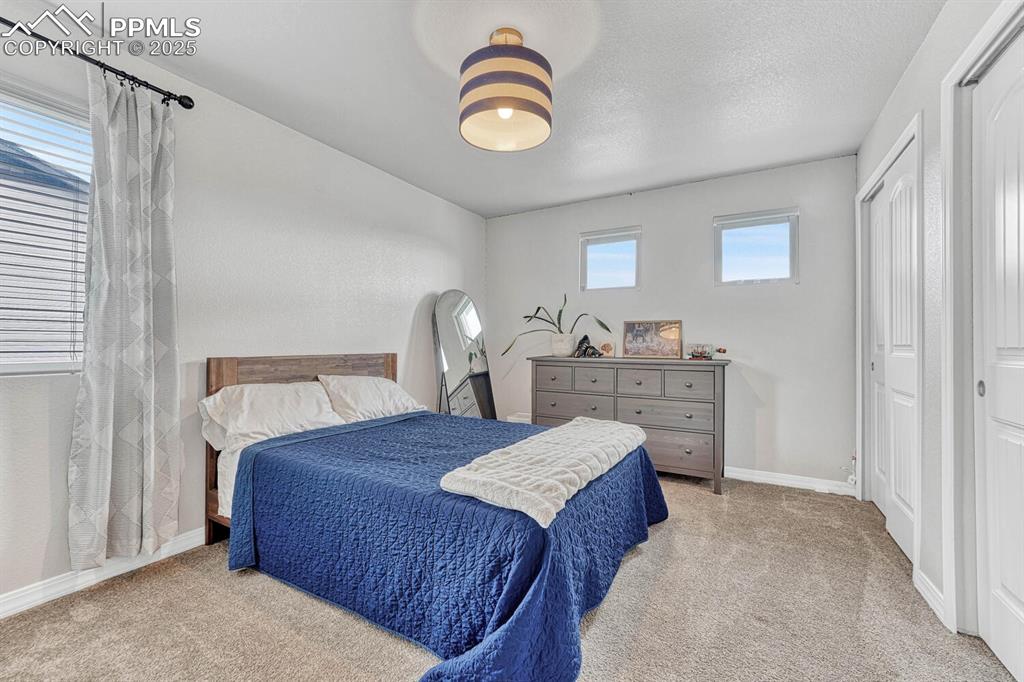 Carpeted bedroom featuring baseboards and a textured ceiling