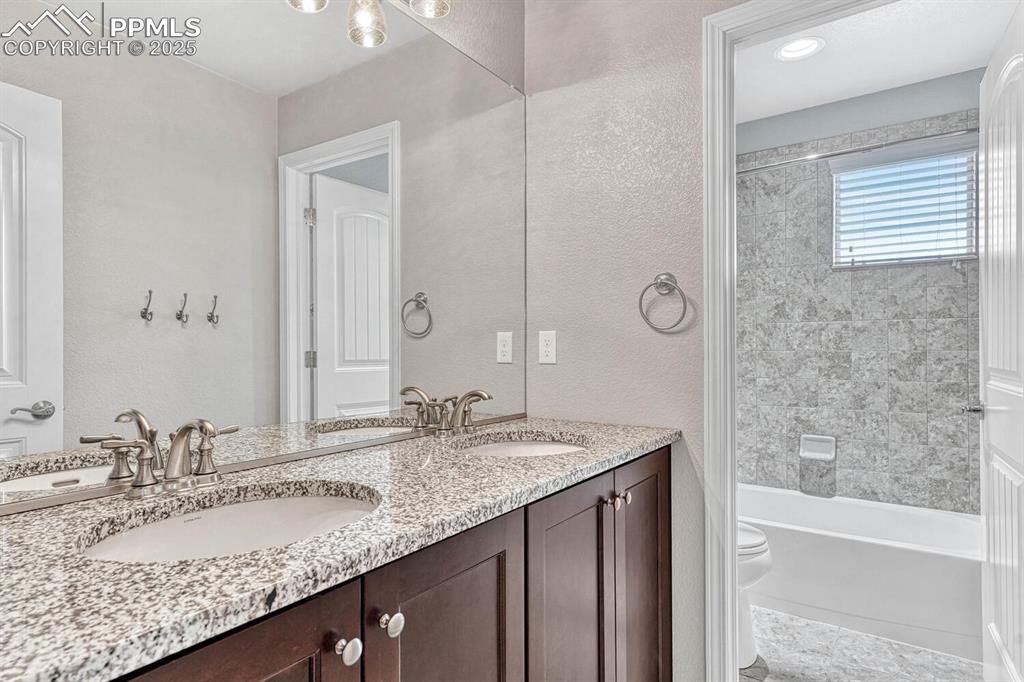 Bathroom featuring a sink, toilet, and double vanity