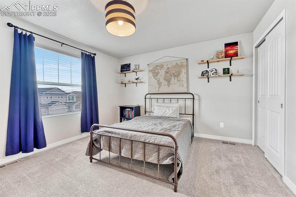 Bedroom featuring a textured ceiling, carpet, visible vents, and baseboards