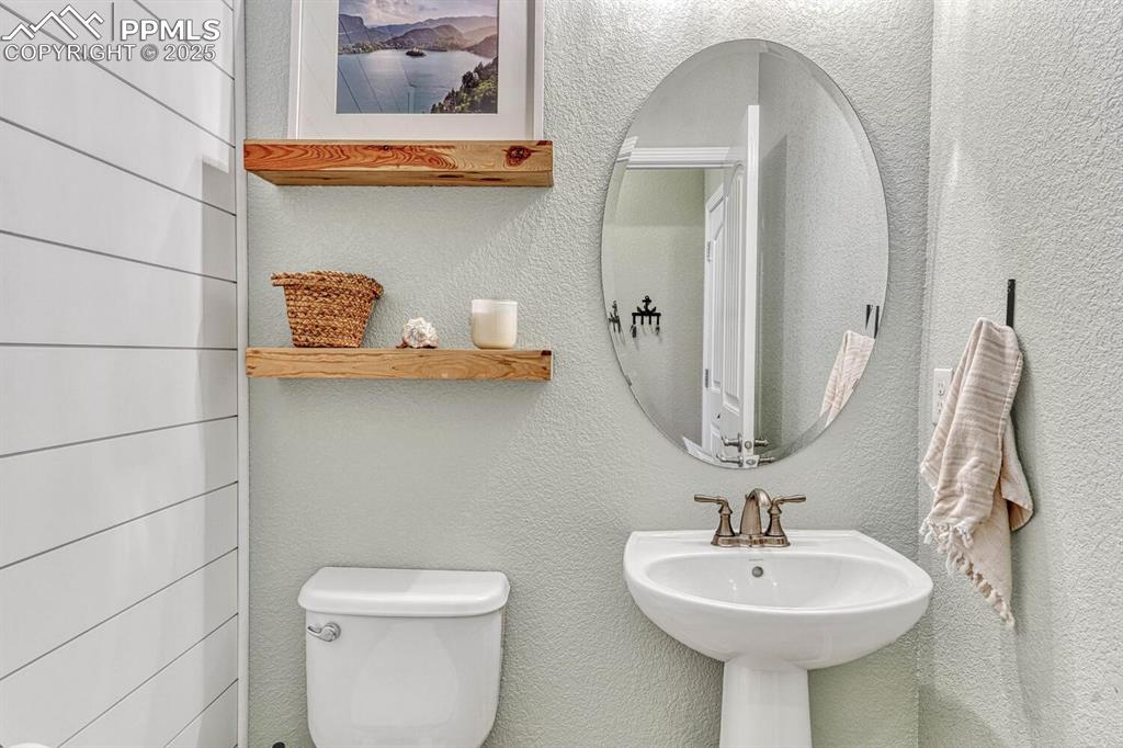 Bathroom featuring toilet, a textured wall, and a sink