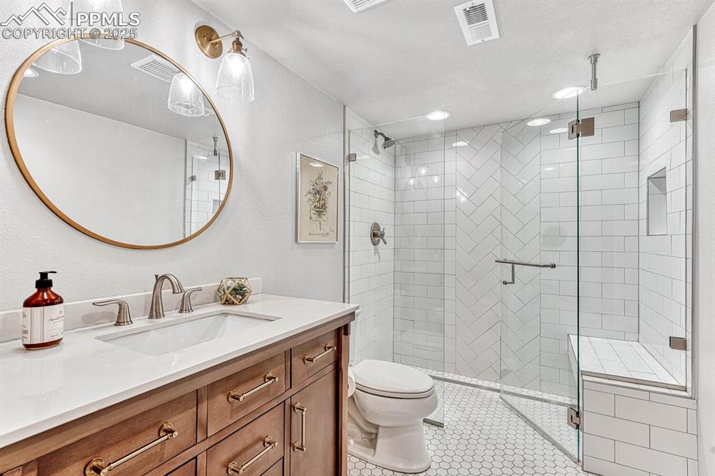 Basement bathroom with a shower stall, toilet, visible vents, and tile patterned floors