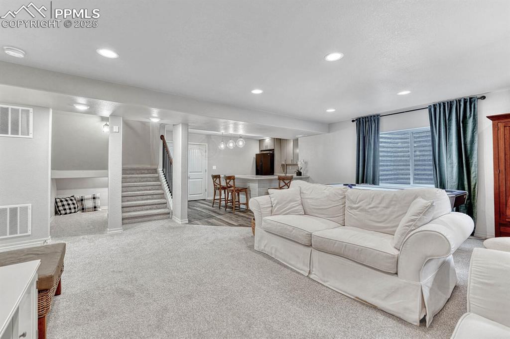 Living area with recessed lighting, visible vents, a bar, and stairway