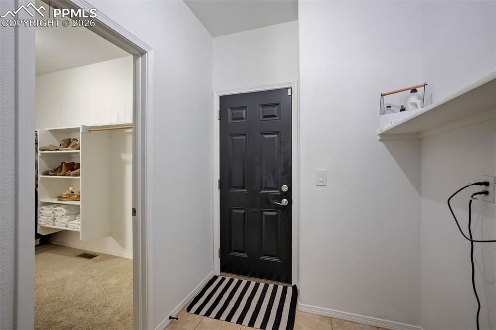 Door to garage with laundry area and access to the primary bedroom walk-in closet