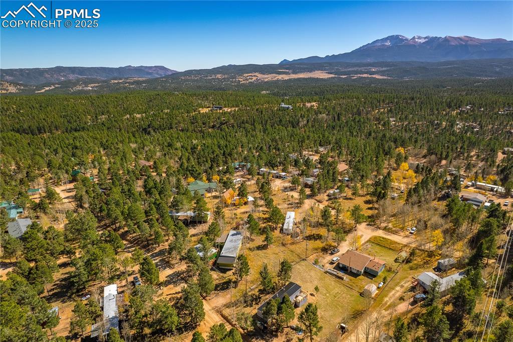 Aerial overview of property's location with a mountainous background and a heavily wooded area