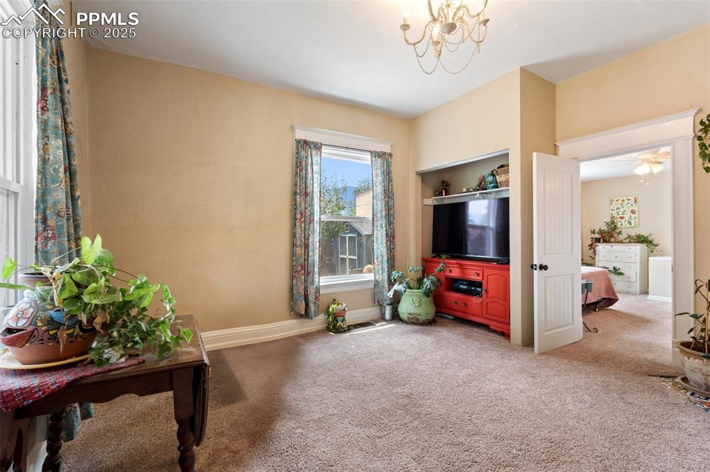 Living area featuring carpet, a chandelier, and ceiling fan