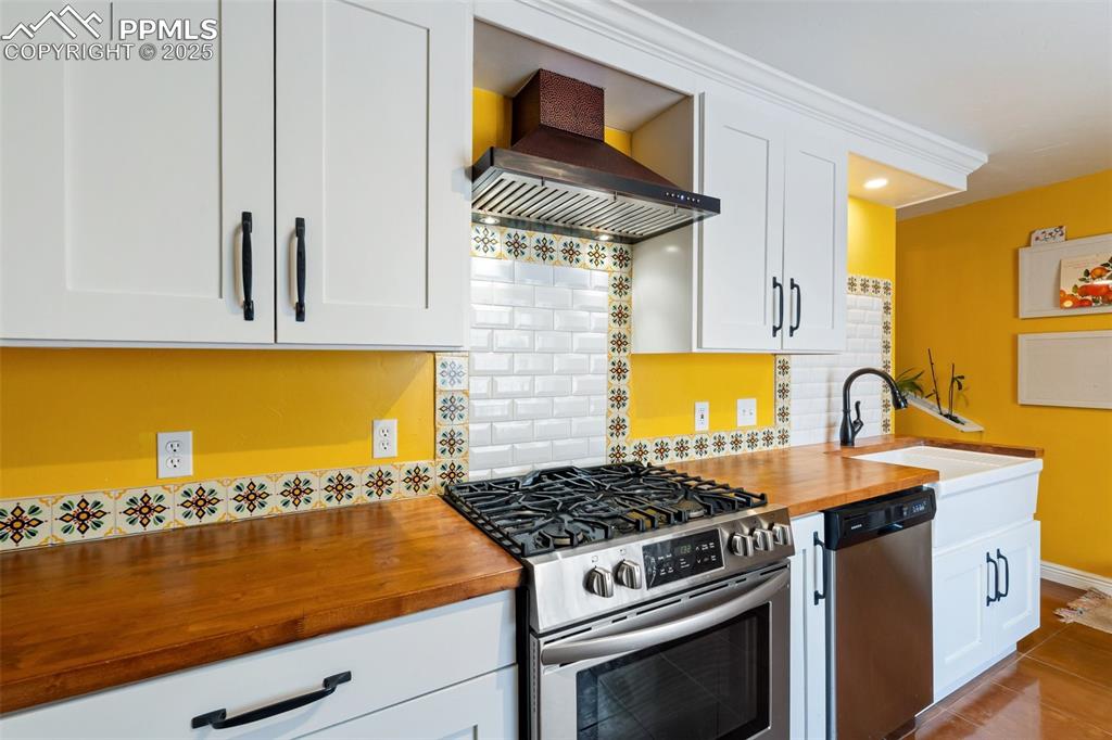 Kitchen with stainless steel appliances, backsplash, and white cabinetry
