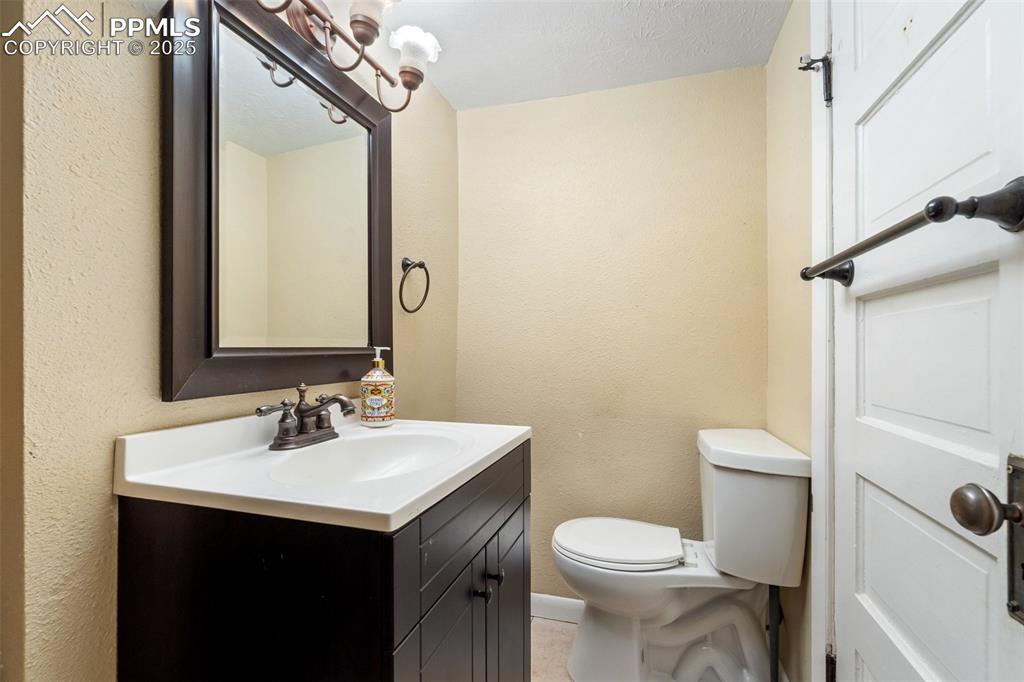 Half bathroom with a textured wall, vanity, and a textured ceiling