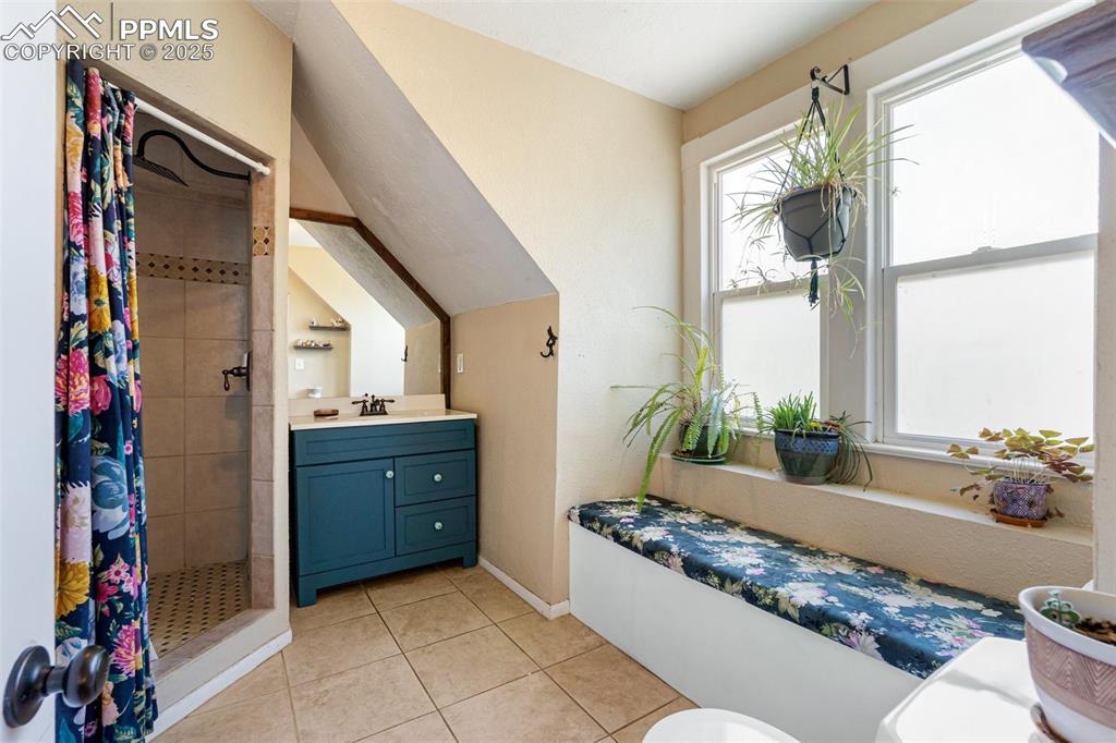 Full bathroom featuring vanity, light tile patterned floors, and a stall shower