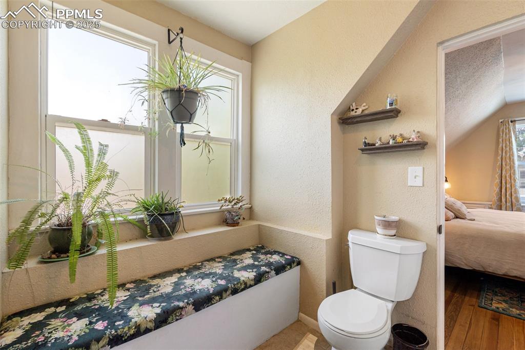 Bathroom featuring a textured wall, connected bathroom, and wood finished floors