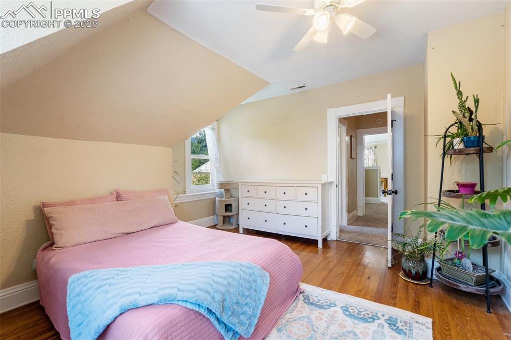 Bedroom featuring wood finished floors, lofted ceiling, and a ceiling fan